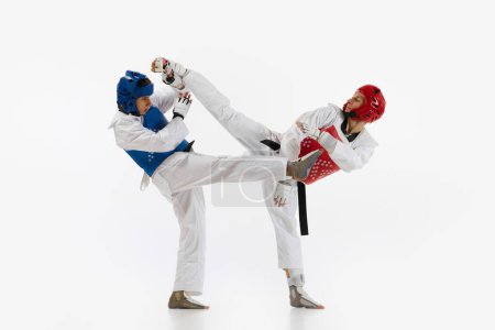 Photo for Athletic, motivated young men, taekwondo athletes in motion, practicing, training isolated over white background. Concept of martial arts, combat sport, competition, action, strength, education - Royalty Free Image