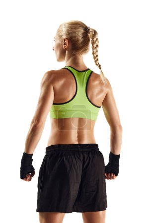 Téléchargez les photos : Vue de dos image de la jeune femme athlétique avec le corps musclé debout dans le pansement de boxe vêtements de sport et isolé sur fond blanc. Concept de sport, mode de vie actif et sain, force et endurance - en image libre de droit