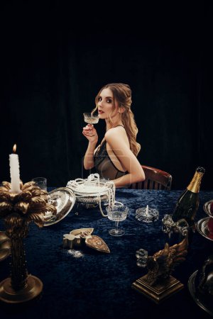 Photo for Portrait of beautiful young woman in elegant dress holding glass with champagne, attending mysterious dinner. Christmas, New Year celebration. Concept of Womens day, event, holiday, beauty, royalty - Royalty Free Image