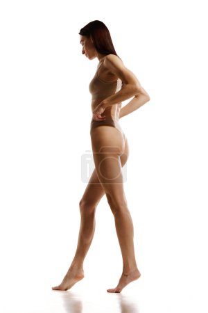Photo for Full-length image of beautiful young woman with slim body in beige cotton underwear on white studio background. Anti-cellulite care, massage, spa. Concept of female beauty, body and skin care, health - Royalty Free Image