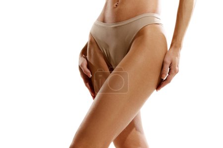Photo for Cropped image of tanned female legs, buttocks in beige cotton underwear against white studio background. Smooth skin. Concept of female beauty, body and skin care, cosmetology, sport, health - Royalty Free Image