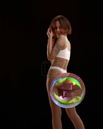 Photo for Young woman with slim body shape, in underwear and soap bubble maximizing body part against black background. Concept of female beauty, body and skin care, weight loss, diet - Royalty Free Image