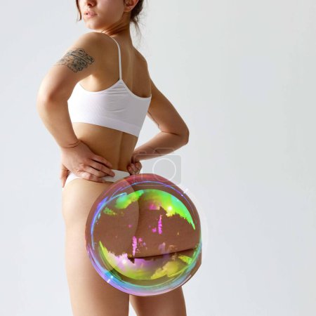 Photo for Young woman with slim, fit body and with soap bubble maximizing buttocks against white background. Anti-cellulite care. Concept of female beauty, body and skin care, weight loss, diet - Royalty Free Image