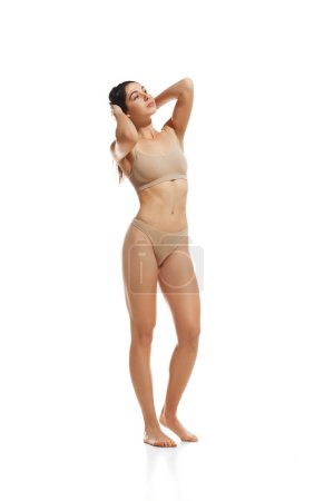 Photo for Full-length image of slim, young, beautiful woman with healthy, fit body, standing in underwear against white studio background. Concept of natural beauty, health and body care, spa, nutrition - Royalty Free Image