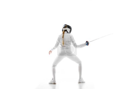 Photo for Women in competitive sports. A female fencer in action, promoting womens participation in competitive sports. Woman, fencer training over white background. Concept of sport, competition, championship - Royalty Free Image