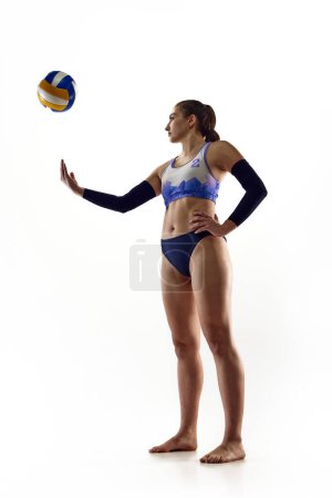 Téléchargez les photos : Image complète de la jeune femme sportive en tenue de sport, joueuse de volley-ball debout avec balle isolée sur fond de studio blanc. Concept de sport professionnel, compétition, match, force - en image libre de droit