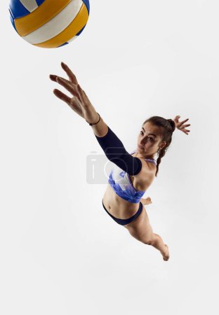 Photo for Top view. Athletic, sportive young woman, beach volleyball player in motion, hitting ball in a jump over white background. Concept of professional sport, competition, match, strength - Royalty Free Image