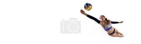 Téléchargez les photos : Jeune femme concentrée et compétitive, joueuse de beach-volley frappant la balle en monition sur fond blanc. Concept de sport professionnel, compétition, match. Bannière. Espace vide pour insérer du texte - en image libre de droit