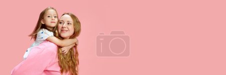 Foto de Retrato de la hermosa joven feliz mujer, madre con su hija pequeña sobre fondo de estudio rosa. Concepto del Día de las Madres, Día Internacional de la Felicidad. Banner. Espacio vacío para insertar texto, anuncio - Imagen libre de derechos