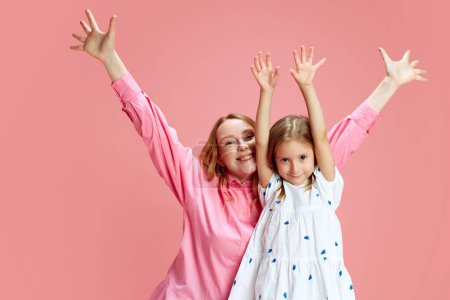 Photo for Cherished motherhood. Portrait of happy young mother and little smiling daughter expressing joy against pink studio background. Concept of Mothers Day, International Happiness Day, motherhood - Royalty Free Image
