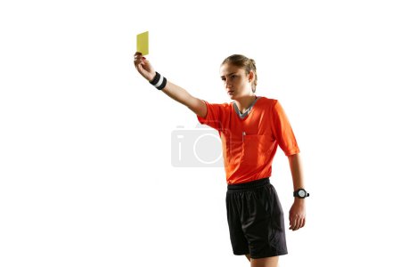 Foto de Mujer joven seria y concentrada, árbitro de fútbol que controla el juego, mostrando la tarjeta amarilla como símbolo menguante sobre el fondo blanco. Concepto de deporte, competición, partido, profesión, juego de fútbol - Imagen libre de derechos