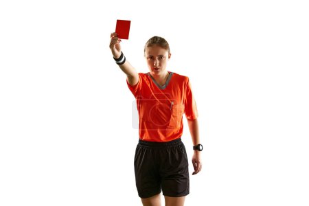 Foto de Mujer joven seria, árbitro de fútbol en uniforme mostrando tarjeta roja como símbolo de despido contra fondo blanco del estudio. Concepto de deporte, competición, partido, profesión, control - Imagen libre de derechos