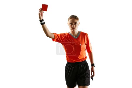 Foto de Mujer joven seria, árbitro de fútbol en uniforme mostrando tarjeta roja como símbolo de despido contra fondo blanco del estudio. Concepto de deporte, competición, partido de fútbol, profesión, control - Imagen libre de derechos