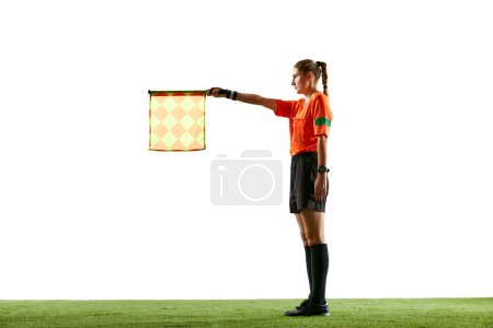 Photo for Assistant referee, young woman in uniform standing on field and raising flag up meaning offside position over white studio background. Concept of sport, competition, match, profession, football game - Royalty Free Image