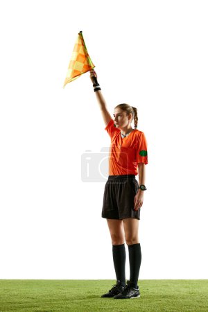 Photo for Stopping game. Young woman, soccer referee raising flag up meaning ball is out-of-play and game need restart against white background. Concept of sport, competition, match, profession, football game - Royalty Free Image