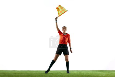 Téléchargez les photos : Arrêt du match. Jeune femme, arbitre de football lever le drapeau ce qui signifie que le ballon est hors jeu et le jeu doit redémarrer sur fond blanc. Concept de sport, compétition, match, profession, match de football - en image libre de droit