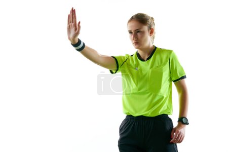 Photo for Young serious woman, soccer referee gesturing, raising hand forward meaning penalty kick against white studio background. Concept of sport, competition, match, profession, football game, control - Royalty Free Image