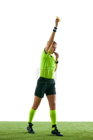 Photo for Serious woman, soccer referee gesturing, raising hand, stopping game and showing yellow card as warning against white studio background. Concept of sport, competition, match, profession, football game - Royalty Free Image