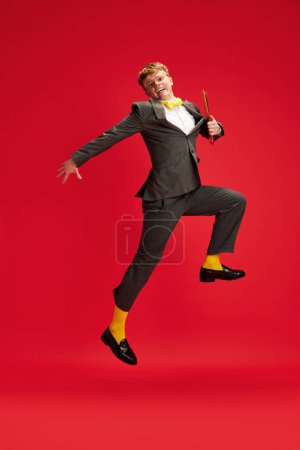 Photo for Full-length image of young man, employee holding documents and cheerfully running against red studio background. Motivation. Concept of business, youth, human emotions, lifestyle - Royalty Free Image