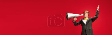 Foto de ¡Anuncio! Hombre Yong en ropa formal hablando en megáfonos contra fondo rojo del estudio. Concepto de negocio, juventud, emociones humanas, estilo de vida. Banner. Espacio vacío para insertar texto, anuncio - Imagen libre de derechos
