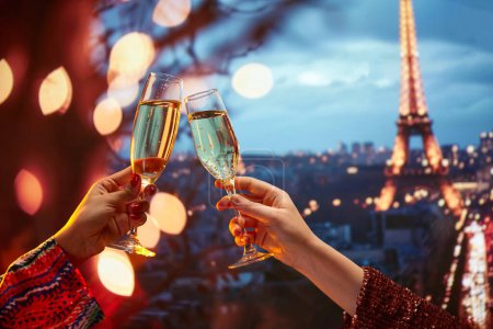 Téléchargez les photos : Luxueuse célébration en France. Les mains féminines cliquetant des verres à champagne sur une vue fascinante du monument parisien. Bonsoir. Concept de vacances, célébration, événements, voyage - en image libre de droit