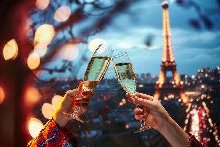 Téléchargez les photos : À la tienne. Fête de la Saint-Valentin à Paris. Des mains humaines accrochant des verres à champagne sur une belle vue sur un monument parisien dans la soirée. Concept de vacances, célébration, événements, tourisme - en image libre de droit