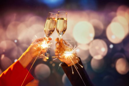 Téléchargez les photos : Nouvel An. Hommes et femmes mains cliquetis verres à champagne sur fond bokeh. Faire des vœux, célébrer des vacances magiques. Concept de vacances, célébration, événements - en image libre de droit