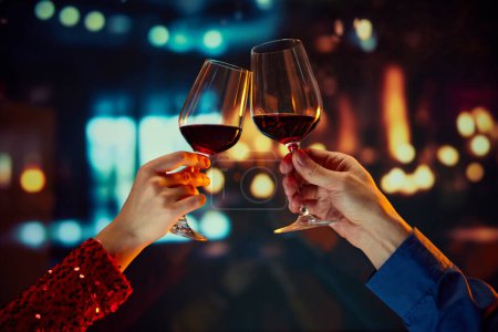 Photo for Valentines Day special promotion at a boutique hotel. Male and female hands clinking glasses with red wine. Anniversary celebration. Romance, Concept of holidays, celebration, events - Royalty Free Image