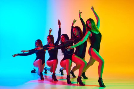 Téléchargez les photos : Jeunes femmes artistiques et expressives en body noir dansant sur des talons hauts sur fond bleu-jaune dégradé au néon. Concept de style de danse moderne, créativité et beauté, art, passe-temps - en image libre de droit