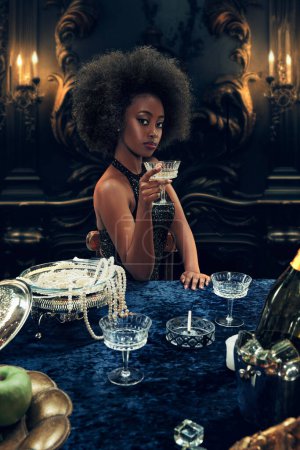 Téléchargez les photos : Portrait d'élégante belle jeune femme africaine en robe pétillante luxueuse soulevant verre avec champagne. Mode de vie riche de la jeunesse. Concept de classe supérieure, vacances, fête, redevance - en image libre de droit