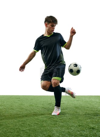 Photo for Young competitive man, soccer playing in motion with ball, training isolated over white background with grass flooring. Concept of sport, game, competition, championship, active lifestyle - Royalty Free Image