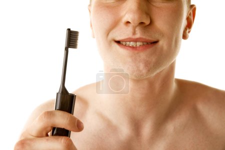 Foto de Imagen recortada de un joven sin camisa parado con cepillo de dientes aislado sobre fondo blanco. Cuidar los dientes, blanquear, cepillarse. Concepto de belleza masculina, cuidado dental, cosméticos, salud - Imagen libre de derechos