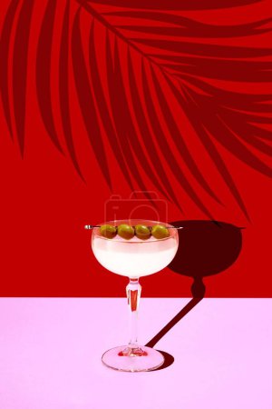 Photo for Contemporary art collage. Refreshing sweet and sour Margarita cocktail stands on pink bar counter against red background with shadows of tropical plants. Concept of parties and holidays, summertime. - Royalty Free Image