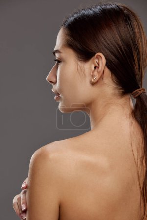Photo for Portrait of young attractive woman with ponytail, well-kept heathy skin standing against studio background. Concept of natural beauty, cosmetology and cosmetics, skin care - Royalty Free Image