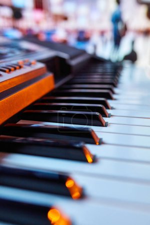 Photo for Close-up of piano keys with blurred silhouettes of people in background. Promotional material for community outdoor piano project. Concept of music instruments, performance, hobby, art, entertainment - Royalty Free Image