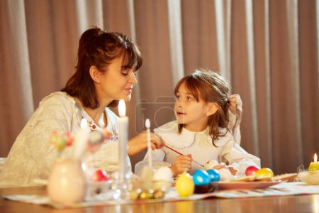 Photo for Beautiful, loving, caring young woman, mother decorating Easter eggs with her little daughter. Holiday preparation, coziness. Concept of holiday, Easter, family, motherhood and childhood - Royalty Free Image