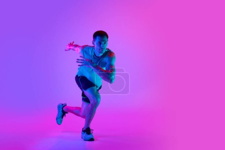 Photo for Warming-up exercises. Sportive young man in sportswear training, doing exercises against gradient pink background in neon light. Concept of active and healthy lifestyle, sport, fitness, endurance - Royalty Free Image