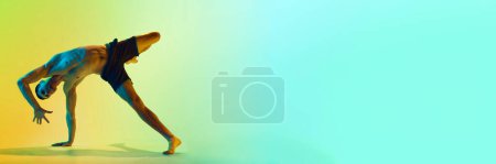 Photo for Dynamic pose. Muscular, athletic young man training shirtless, practicing against gradient blue yellow background in neon. Active and healthy lifestyle concept. Banner. Empty space to insert text, ad - Royalty Free Image