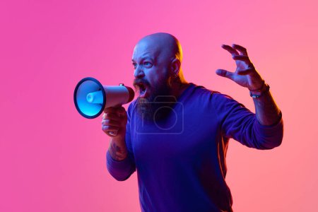 Photo for Emotional bearded man with serious face, shouting in megaphone with hand raised against pink background in neon light. Concept of human emotions, facial expression, news, announcement, control - Royalty Free Image