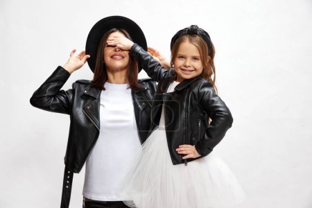 Photo for Celebration. Happy young woman, mother covering eyes, standing her happy little daughter against white studio background. Concept of happiness, Mothers day, childhood, fashion and lifestyle - Royalty Free Image