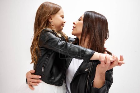 Photo for Tender, bonding moment. Happy mother sanding with little daughter, embracing, showing love and care against white studio background. Concept of happiness, Mothers day, childhood, fashion, lifestyle - Royalty Free Image