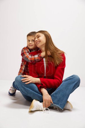 Photo for Family portrait of beautiful young mother embracing with little boy, son against white studio background. Casual style outfits. Concept of happiness, Mothers day, childhood, fashion and lifestyle - Royalty Free Image