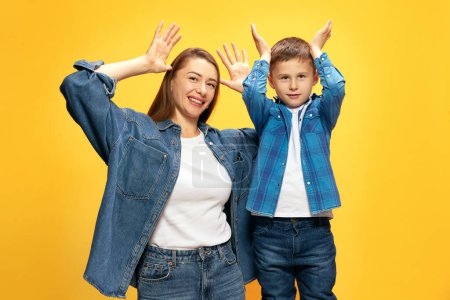 Photo for Playful happy family. Mother spending good timer with her little son, playing and laughing against yellow studio background. Concept of happiness, Mothers day, childhood, fashion and lifestyle - Royalty Free Image