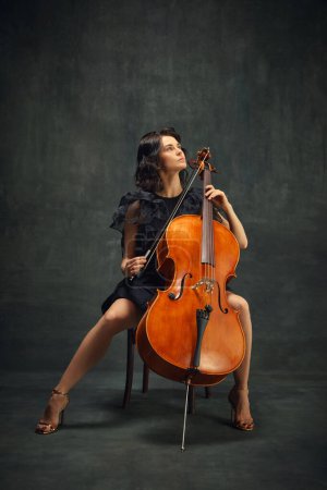 Hermosa mujer, violonchelista mirando hacia arriba, reflejando creatividad e inspiración mientras toca. Promoción del evento de música clásica en vivo. Concepto de arte clásico, estilo retro, música, inspiración