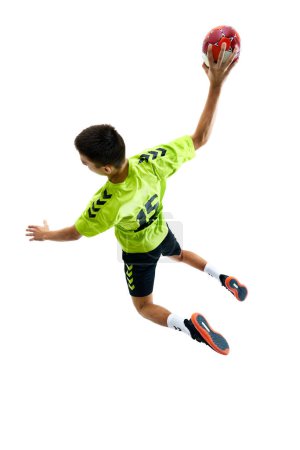 Téléchargez les photos : Image de vue de dessus du jeune gars, joueur de handball en mouvement pendant le jeu, l'entraînement sur fond de studio blanc. Concept de sport professionnel, tournoi, compétition - en image libre de droit