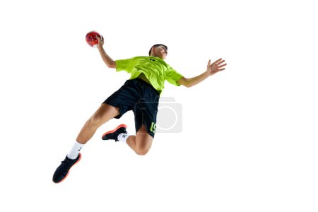 Téléchargez les photos : Image de vue du bas du jeune gars, athlète de handball en mouvement pendant le jeu, jouer, pratiquer sur fond de studio blanc. Concept de sport professionnel, tournoi, compétition - en image libre de droit