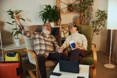 Photo for Happy, relaxed senior couple, man and woman sitting at home with tickets, dreaming about upcoming trip, planning. Concept of vacation, traveling, booking services - Royalty Free Image