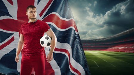 Photo for Young concentrated man, soccer payer in red uniform standing on filed with ball, representing team of England. Concept of live sport event, championship, match and tournament - Royalty Free Image