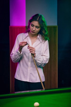 Photo for Young woman preparing cue with chalk over billiard table. Poster featuring leisure sports theme. Concept of billiards sport, gambling, hobby, leisure, game - Royalty Free Image