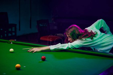 Photo for Focused young woman playing snooker game, aiming cue on balls. Online course banner for mastering billiards skills. Concept of billiards sport, gambling, hobby, leisure, game - Royalty Free Image